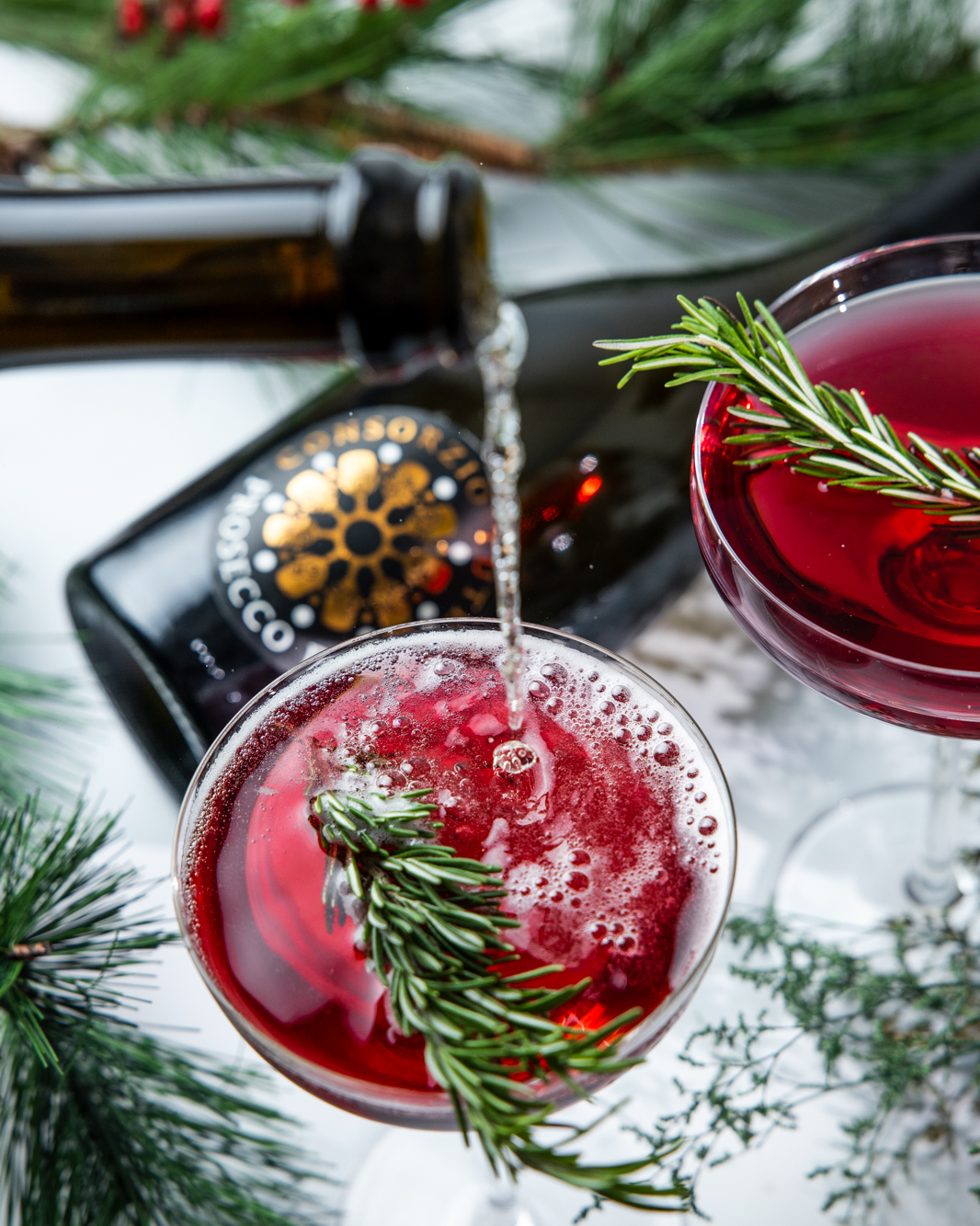 A red cocktail being topped with Prosecco